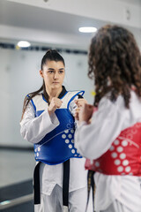 Two taekwondo girls in combat practicing on training at martial art school.