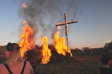 Das Osterfeuer ist angezündet: Ein Brauch zum religiösen Fest mit flammenden Kreuz und Menschen auf dem Acker.