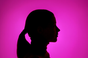 Profile of a dark female silhouette on a purple background close-up.