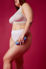 Cropped portrait of young overweight woman in inner wear holds in hands blue toy for adults against...