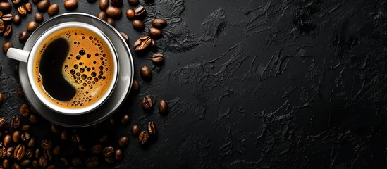 Washable wall murals Coffee bar cup of black coffee surrounded by coffee beans on rustic black background 