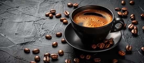 Keuken spatwand met foto cup of black coffee surrounded by coffee beans on rustic black background  © Menganga