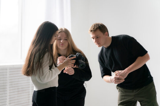 Young Photographer Demonstrates Camera Results to Two clients in Bright Indoor Setting