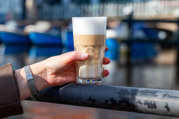 A female with a cup of latte coffee in her hand. 