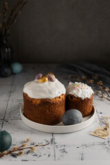 Easter still life with decorated homemade cakes-panettone, painted eggs and willow twigs on a dark background. Traditional treats for the Bright Resurrection of Christ in the Christian religion. 