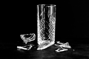 Broken drinkglass with pieces of broken glass around it. 