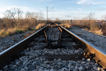 Rails with wood tie and overhead line during sunny evening, railroad transportation