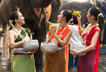 Young pretty women in traditional Thai clothing with jasmine flower garland splashing water...