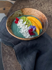 Spirulina smoothie bowl with mango kiwi and coconut flakes, beautifully decorated. Healthy food. 