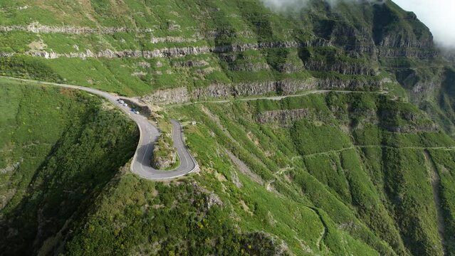 Drone fly along sharp Madeira hairpin turn on lush Madeira hillside cliff