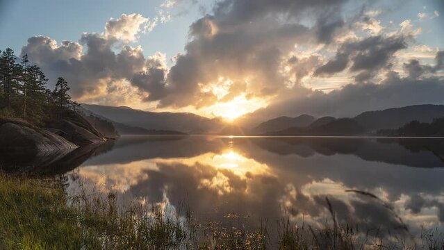A beautiful sunset above the calm lake and pine forest.