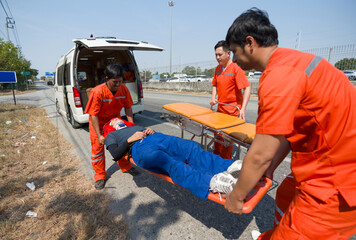 Group of paramedic or emergency medical technician (EMT) in orange uniform helping neck and head...