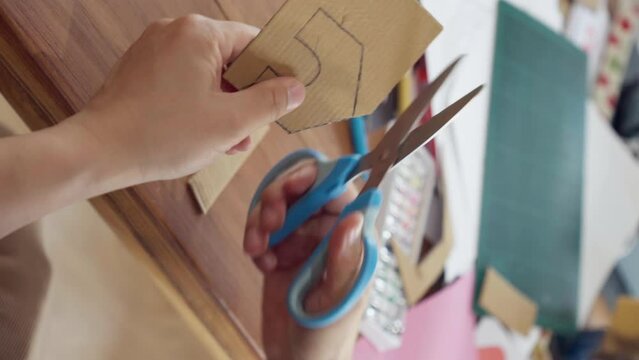Close up of hand using scissors cut a house on cardboard
