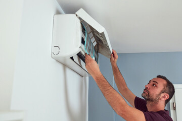 Man cleaning and maintaining air condition unit.