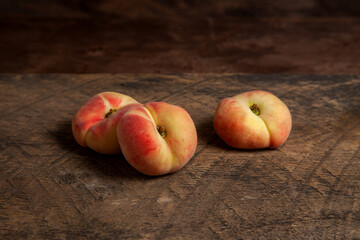 Three saturn peaches or flat peach on wooden background..