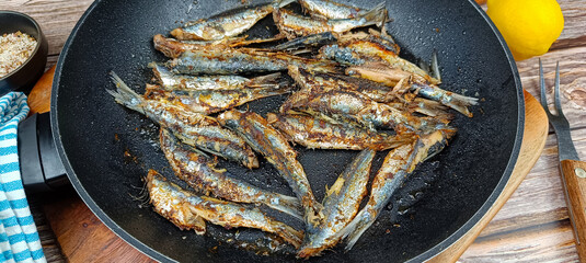 Plusieurs sardines en cuisson dans une poêle. Gros plan.	