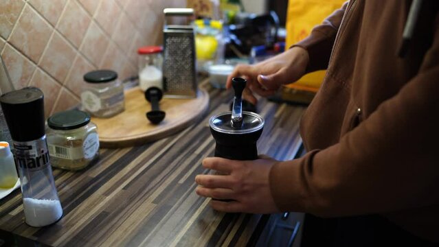 Man grinds coffee in a manual coffee grinder in the kitchen. High quality 4k footage