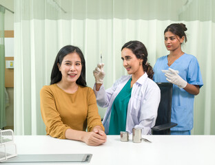 Doctor in white gown and protective glove prepare to give an injection to a female patient.