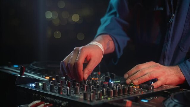 Deejay is mixing music on a musical instrument accessory at art festival, providing entertainment for the audience. The electronic instrument is creating a vibrant concert atmosphere