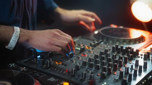 Deejay providing entertainment playing music on mixing console in dark room. Sound engineer scratching to enhance audio experience at event