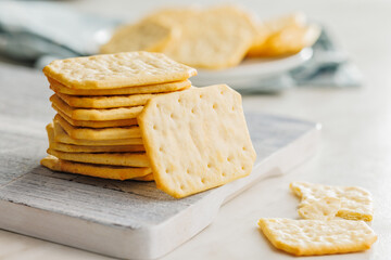 Golden Baked Crackers on cutting board on a White kitchen table.