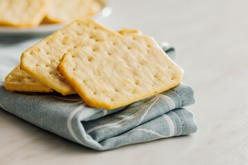 Golden Baked Crackers on napkin on a White kitchen table.
