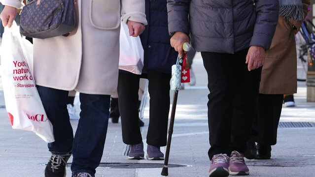 杖をついて歩く高齢の女性