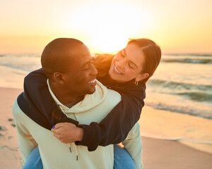 Casually Dressed Loving Couple With Man Giving Woman Piggyback Ride On Beach Shoreline At Sunrise