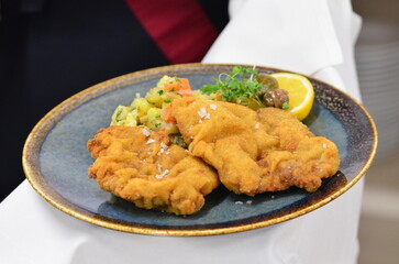 Schnitzel with potatoes and herbs on a plate in a restaurant