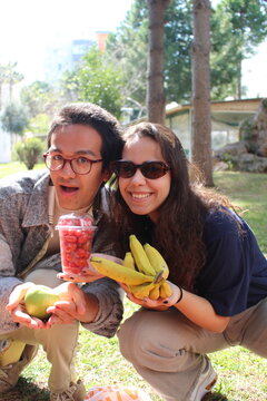 two friends out on a picnic in the garden  holding healthy fresh fruits *7