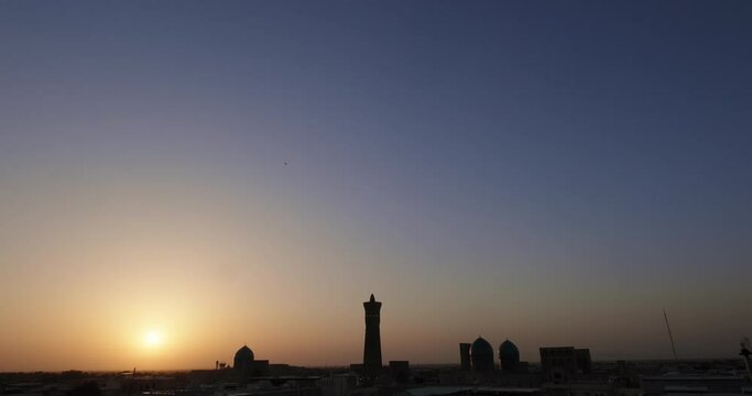 Silhouette of Po-i-Kalyan or Poi Kalan complex at sunset. Old Bukhara from the roof at sunset. Handheld shoot
