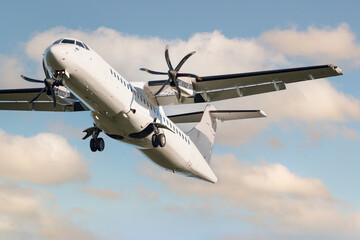 ATR 72 airplane among the clouds.  Twin-engine turboprop short-haul regional passenger aircraft....
