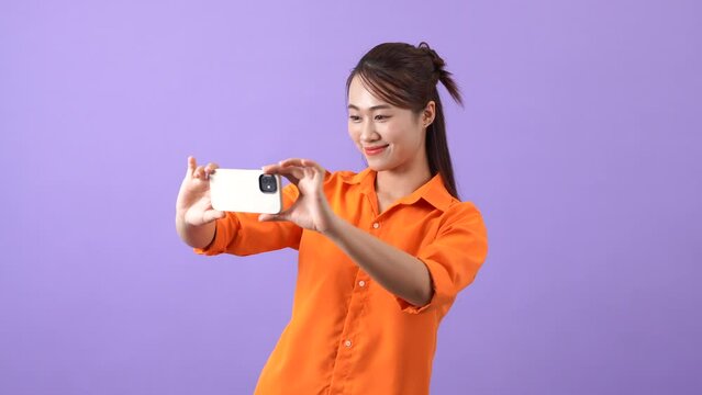 Asian woman is using her phone to take a photo
