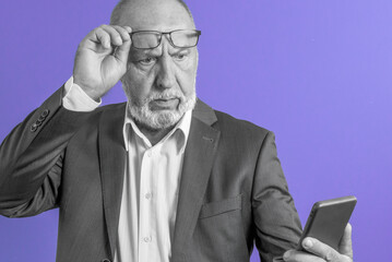 Vision problems in old people. Portrait of a man with poor vision wearing glasses using a smartphone