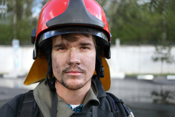 Portrait of fireman wearing fire fighter turnouts and red fire helmet to protect head, closeup