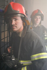 Two firemen in protective suits and protective masks in system of labyrinths for working out skills...