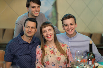 group portrait of smiling, cheerful friends (three men and one woman with releases) on holiday, feast