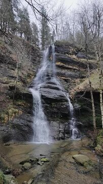 a tranquil waterfall cascading down rocky terrain amidst bare trees, showcasing nature&rsquo;s serene and natural beauty in uguna, bas que country