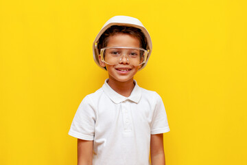 african american boy builder in hard hat and safety glasses smiling on blue isolated background