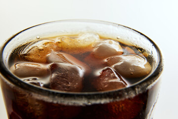 Glass wit foamy drink, soda water, coke, dark beer with ice cubes against white background. Concept of alcohol and non-alcohol drinks, refreshment. Poster, banner for ad