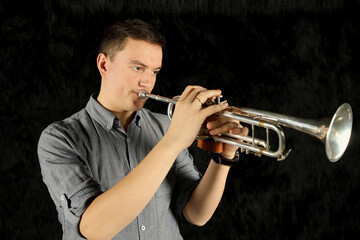 Portrait of trumpet player in gray shirt in black room © Pavel Losevsky