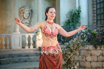 Portrait of beautiful woman in red dress decorated with pearls is dancing Arabic dance