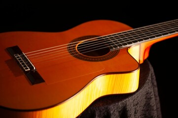 Obraz premium Classical Spanish flamenco guitar close up, dramatically lit isolated on black background with copy space.