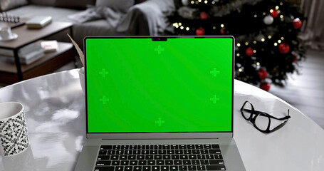 Laptop place on living room table, Christmas and New Year mood, Green screen display, Close up monitor of notebook with mock up