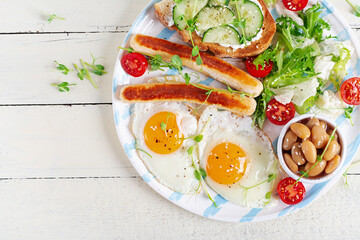 English breakfast. Keto breakfast. Fried egg, beans, chicken sausage. Top view, flat lay