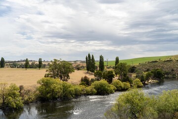 flowing river past farmland in summer, in the Tasmania wilderness. Lake with a Sandy beach and trees in Australia