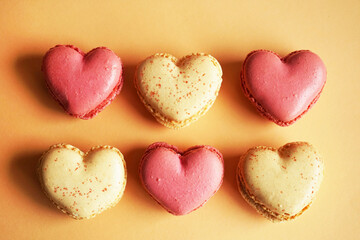 Obraz premium Macarons in the shape of hearts on a pink and yellow background