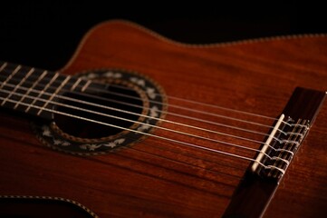 Classical Spanish flamenco guitar close up, dramatically lit isolated on black background with copy...