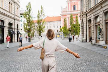 Smiling woman wearing stylish outfit walking on street of Ljubljana old town, Slovenia.Travel Europe - 762269664