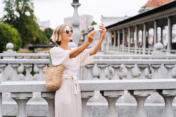 Happy female using smart phone on the Triple bridge in Ljubljana, Slovenia, Europe.